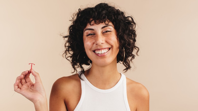 Model smiling while holding IUD