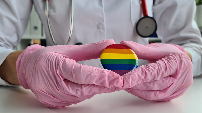 Medical professional holding Pride flag badge