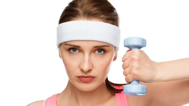 Woman wearing sweat band, holding a dumbbell
