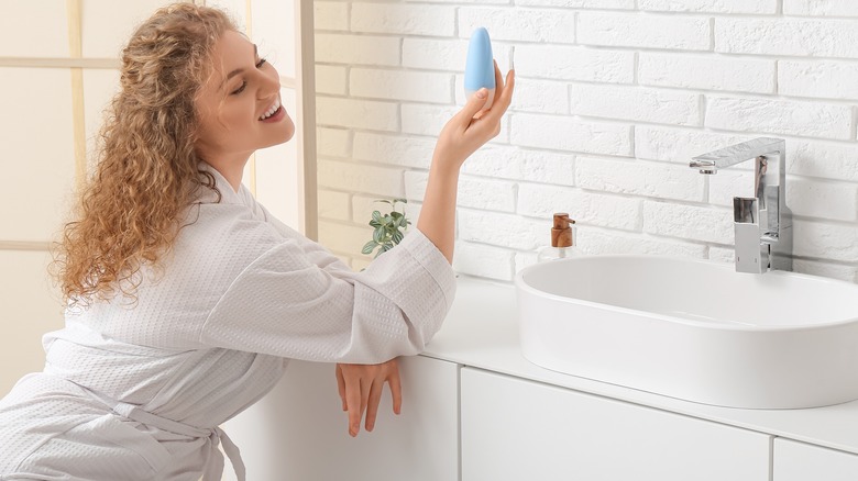 Woman in bathroom viewing deodorant