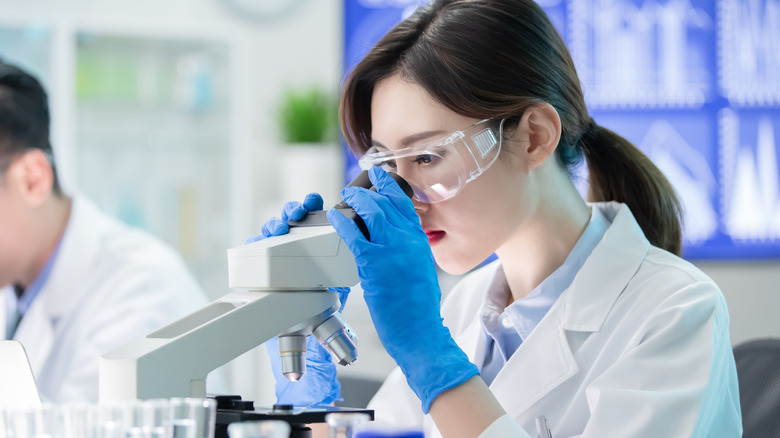 scientist looking through microscope