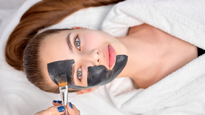 professional applying face mask on woman