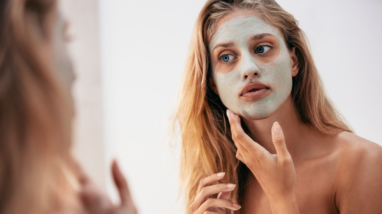 woman applying green clay face mask