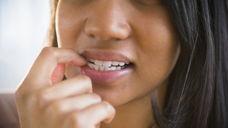 woman with dark hair biting nails