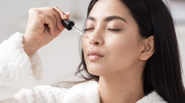 Woman applies serum to face 