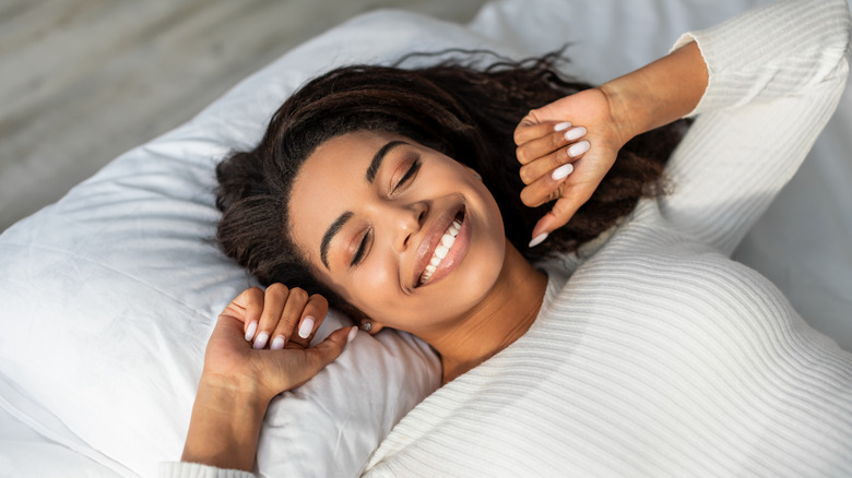 smiling woman stretching in bed
