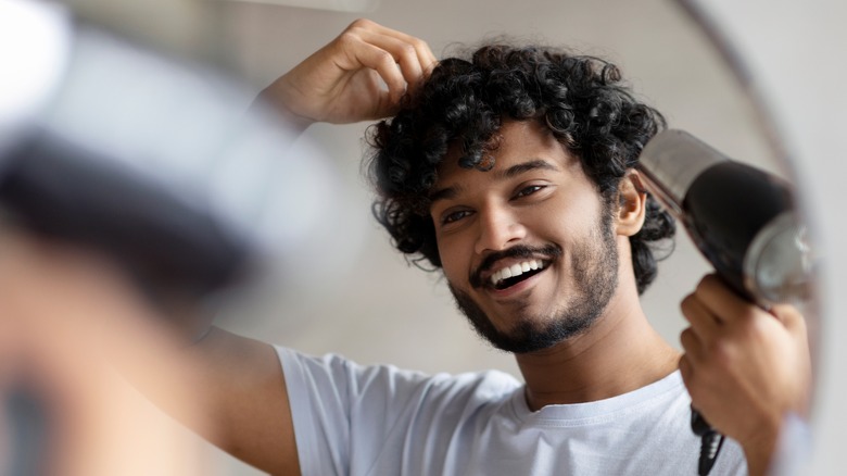 Curly haired man and blow dryer