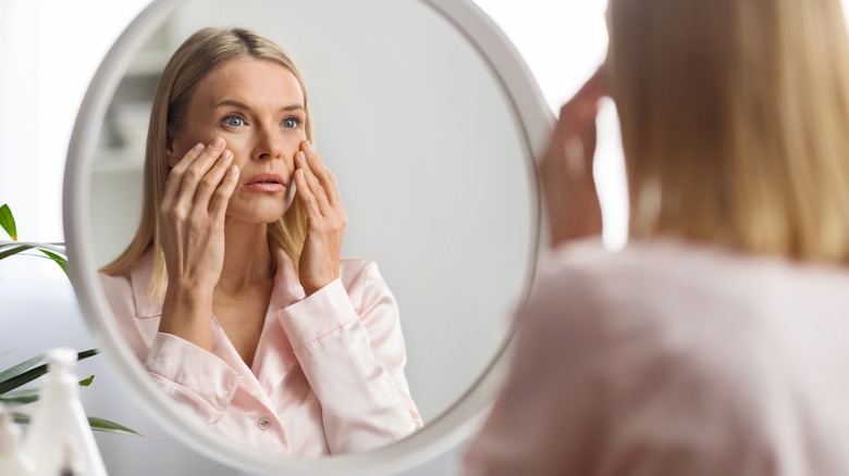 woman inspecting her skin in mirror