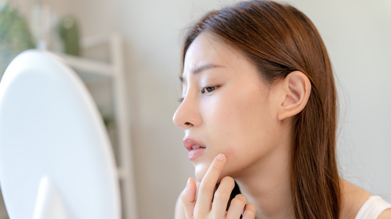 Woman touching large pimple