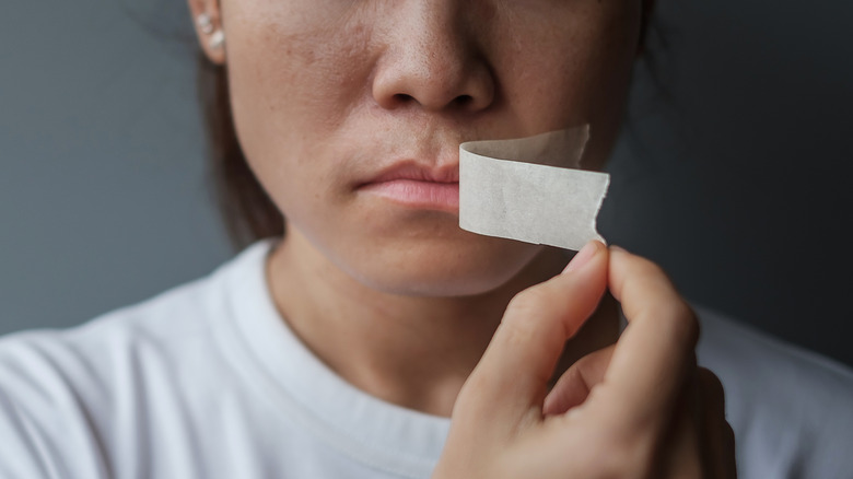 woman removing tape from mouth