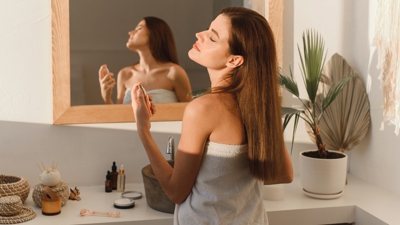 Female spraying perfume on neck