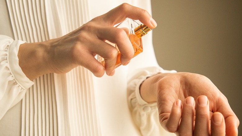 Person spraying perfume on wrist