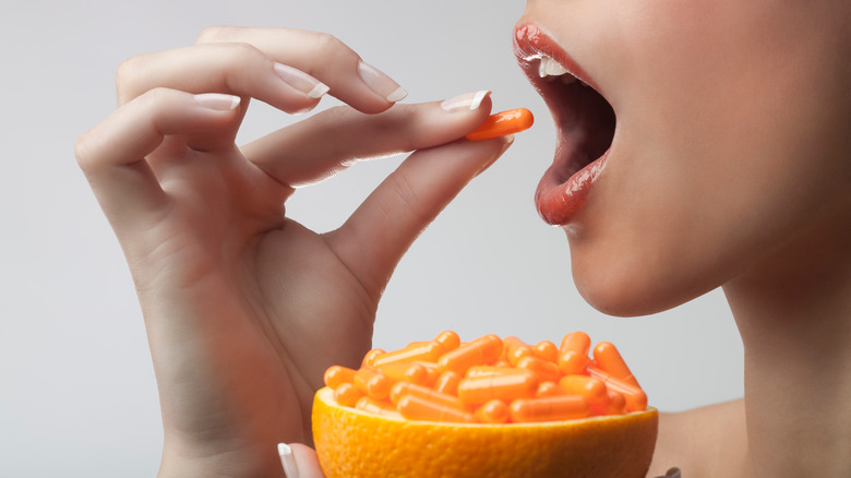 women eating orange full of pills