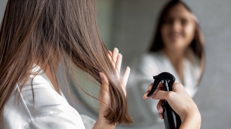 Woman spraying hair with product