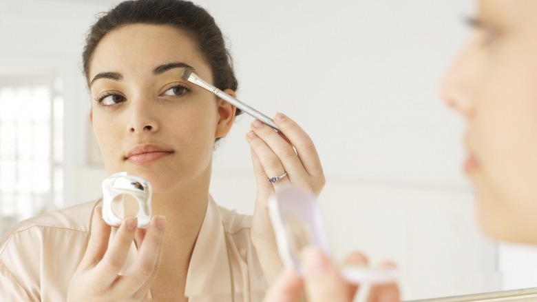 Woman doing makeup in mirror