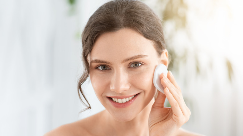 woman applying toner and smiling