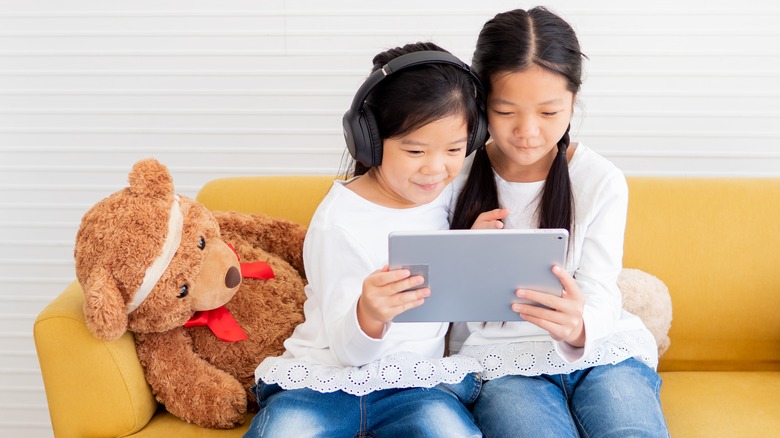 Two child sisters watching tablet