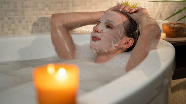 A woman taking a bath while wearing a sheet mask.