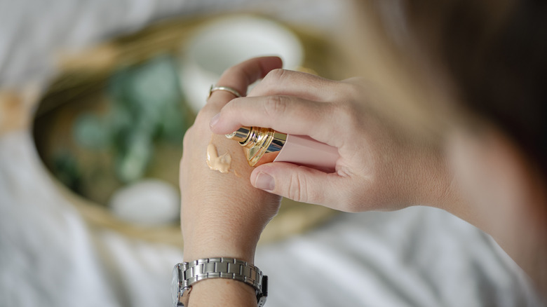 A woman putting makeup foundation on her hand.