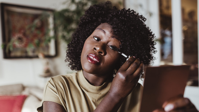 A woman applying mascara.