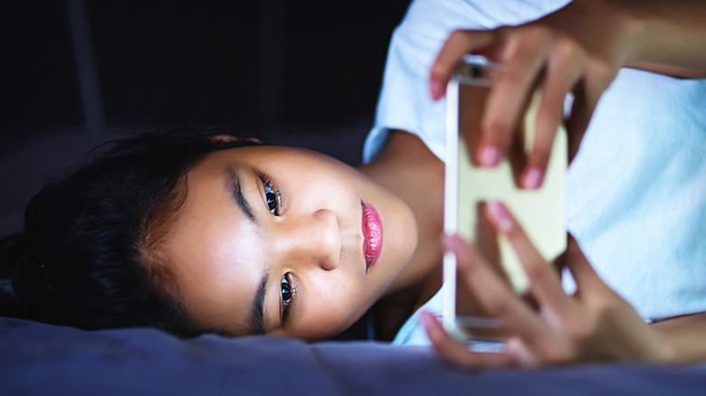 Asian woman using phone in bed