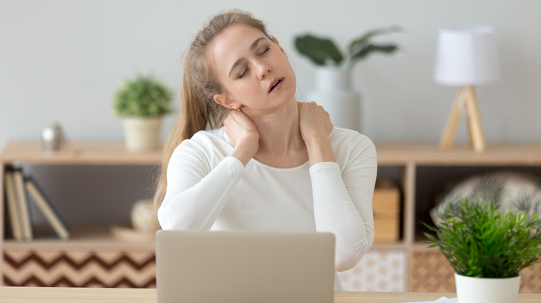 Woman massaging shoulders in front of computer