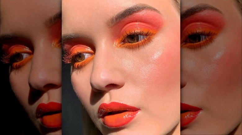 woman with orange eyeliner, pink eyeshadow, and orange lipstick
