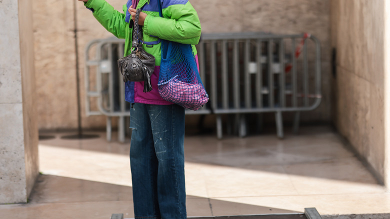 woman holding mesh bag and handbag