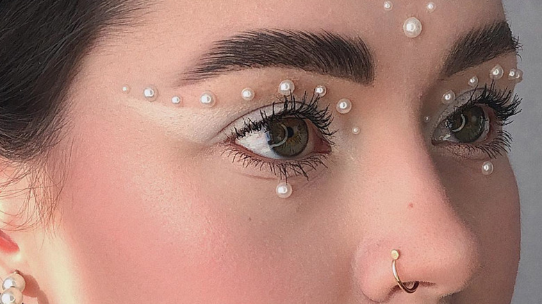 A woman with white eyeliner and pearls