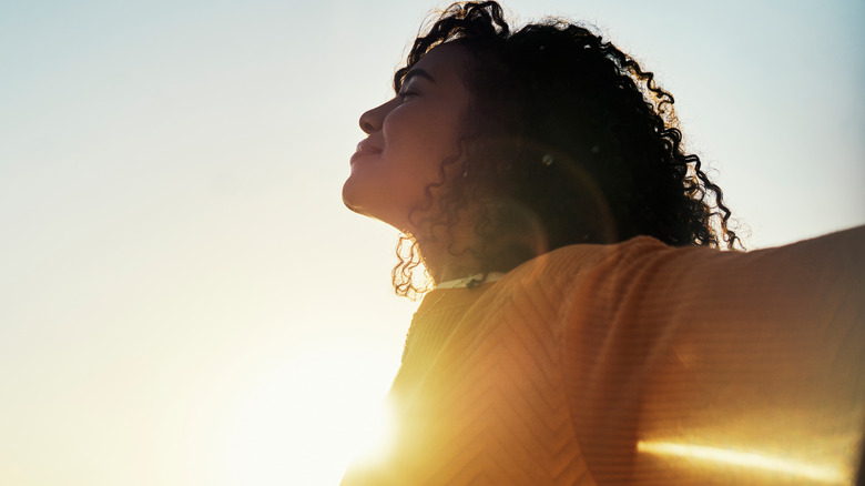 Woman opens arms by sun