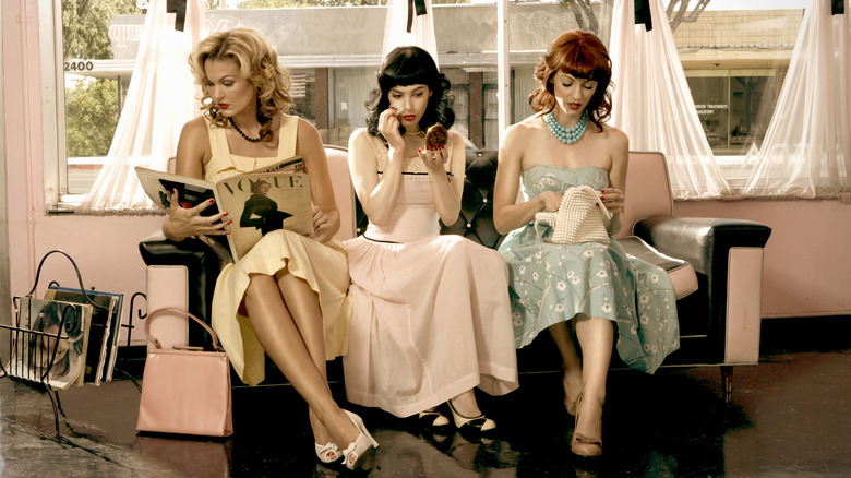 Women sitting while wearing vintage dresses.