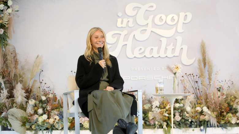 Gwyneth Paltrow sitting in front of In Goop Health sign onstage