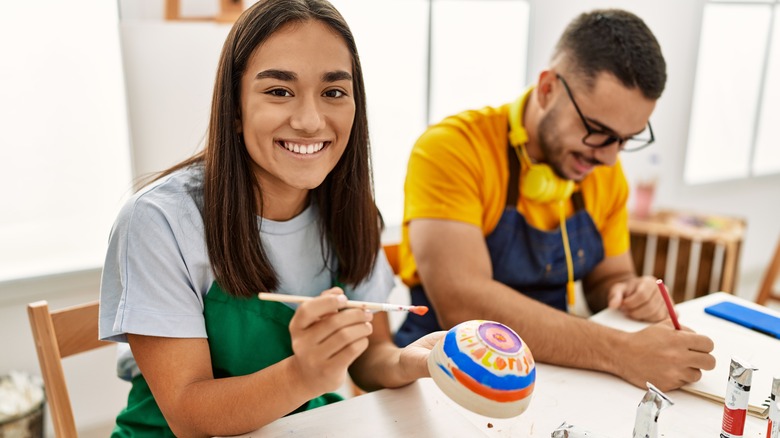 woman and man painting pottery 