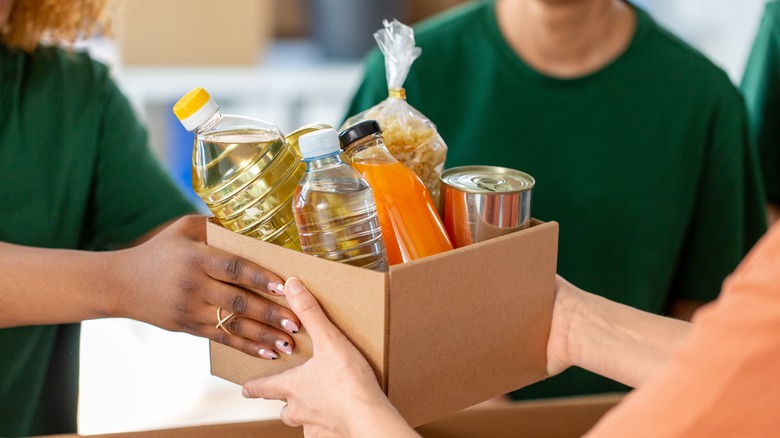 volunteers hand off a box of food