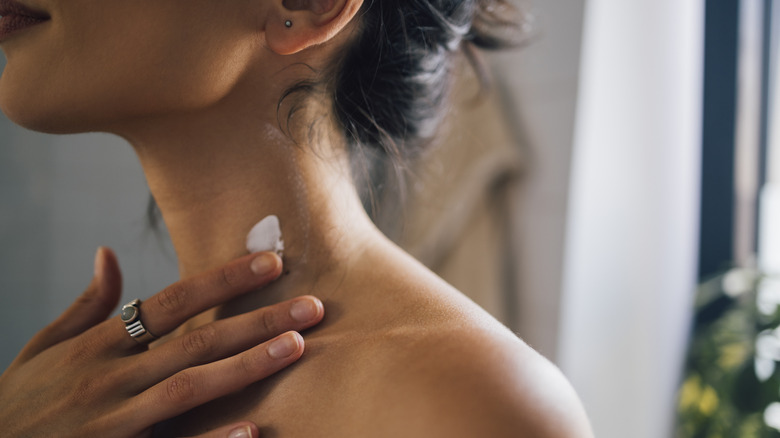 girl applying moisturizer to neck