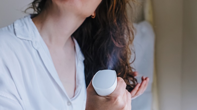 A woman applying spray to her hair