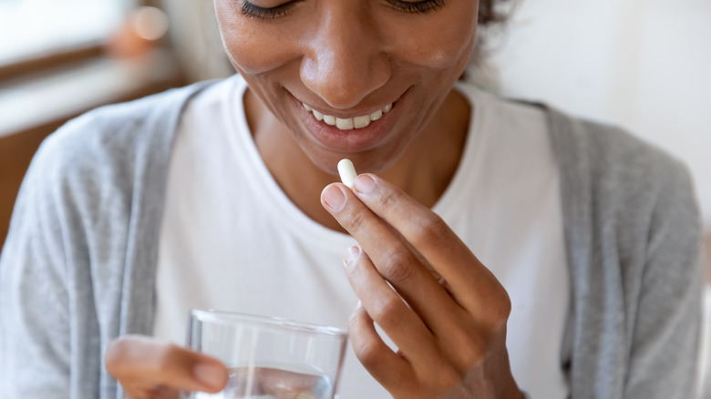 Woman taking pill with a glass of water