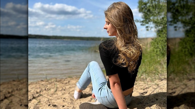 Woman poses on beach with wavy earth blond hair