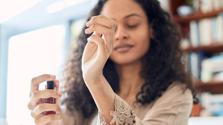 woman spraying perfume on wrist