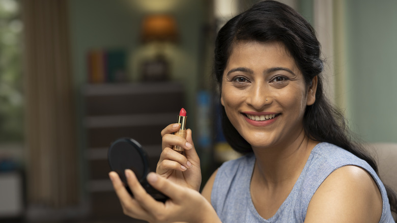 Smiling woman holding lipstick