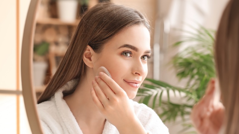 Woman looking at mirror applying makeup