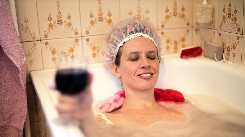Woman wears shower cap in bathtub 