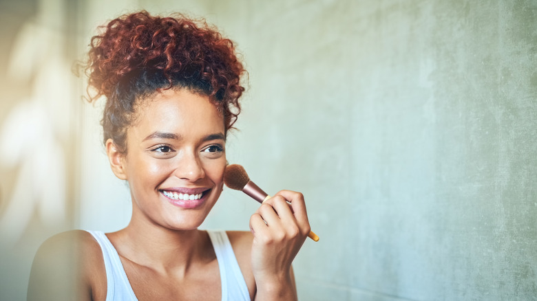 woman applying powder to face