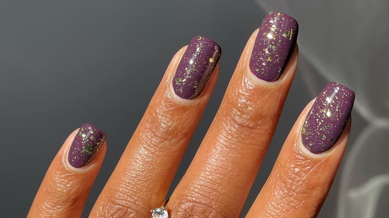 purple manicure with gold flakes
