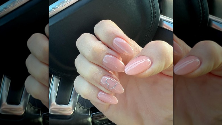 Neutral pink nails with silver heart detail on ring finger