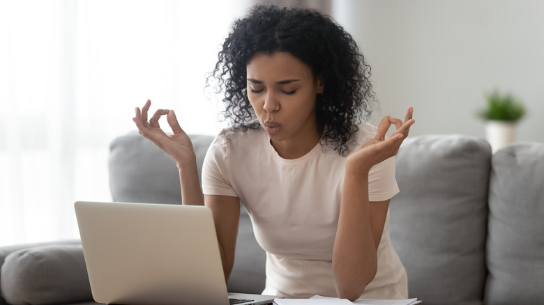 Woman sitting, meditating near laptop