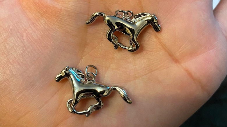 Silver horse pendants on a hand