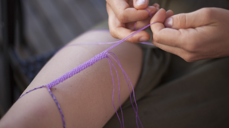 Woman tying macrame bracelet