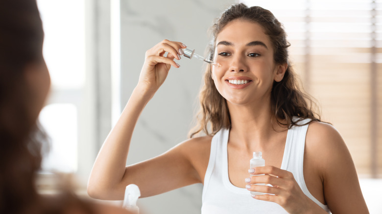 Woman applies serum to face