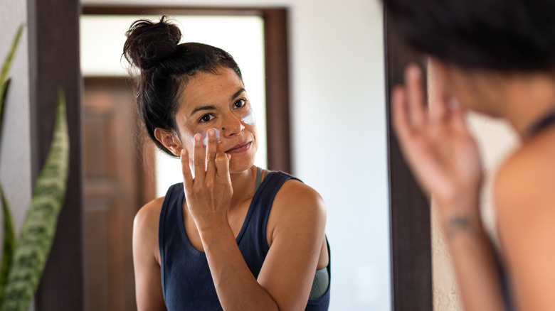 Woman applying face moisturizer